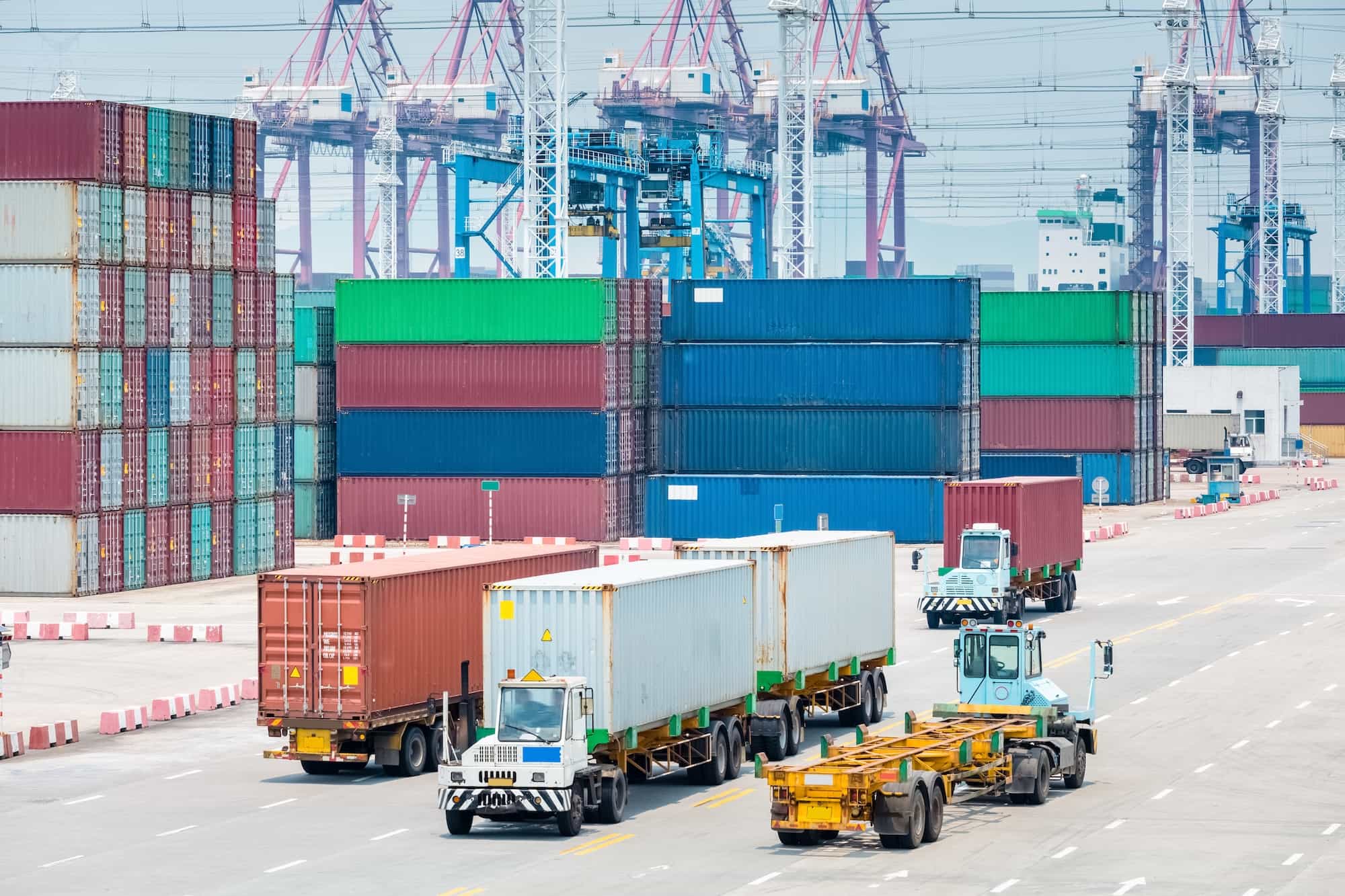 Container port with trucks and stacked shipping containers